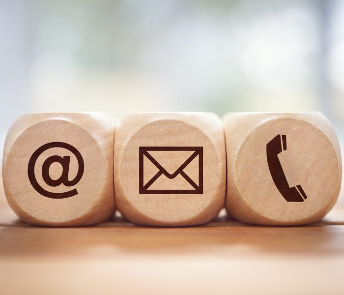 Contact us concept with wood block and symbols at, e-mail address and phone